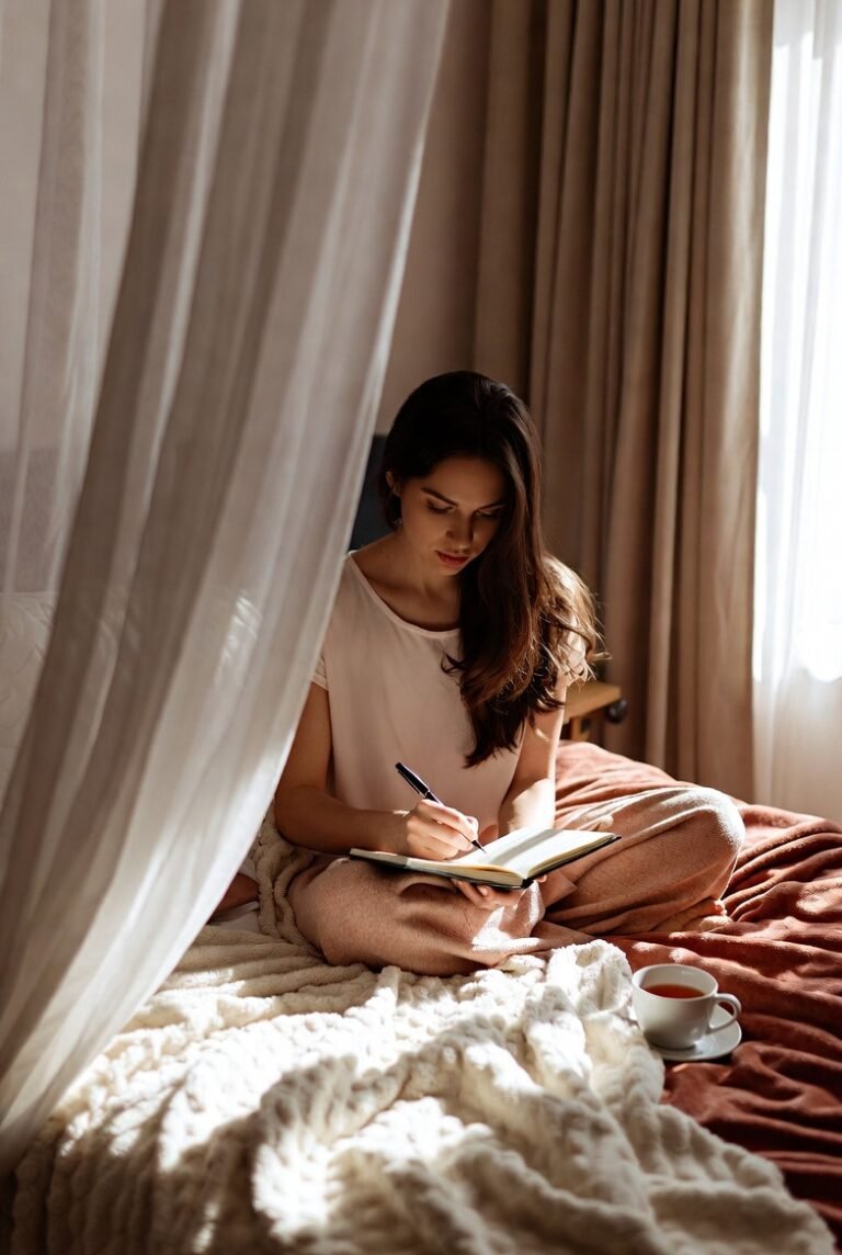 Woman writing in a journal by a sunlit window, illustrating journaling prompts for self-growth and personal transformation